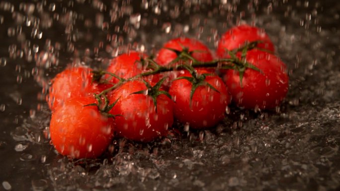在慢镜头中，水洒在樱桃番茄上