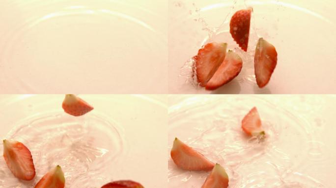 草莓片以慢镜头落在白色潮湿的表面