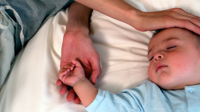 慢镜头中，母亲和熟睡的男婴躺在床上