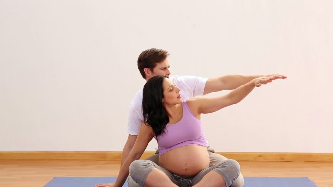 理疗师伸展与他的怀孕病人在一个健身工作室