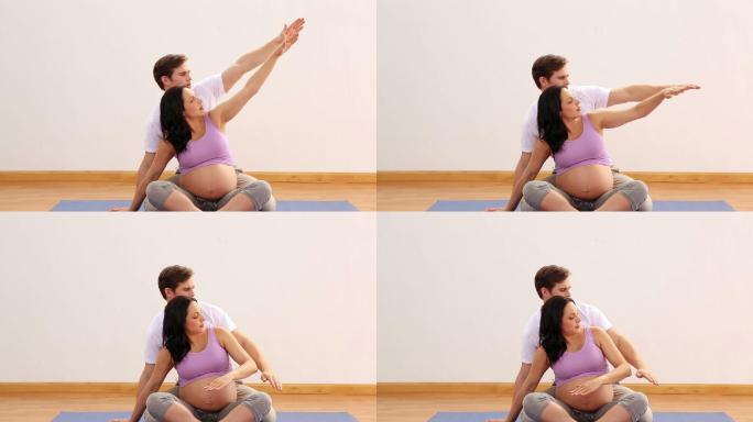 理疗师伸展与他的怀孕病人在一个健身工作室