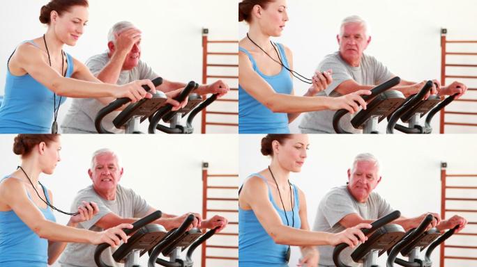一个老人和他的教练在康复中心使用健身自行车