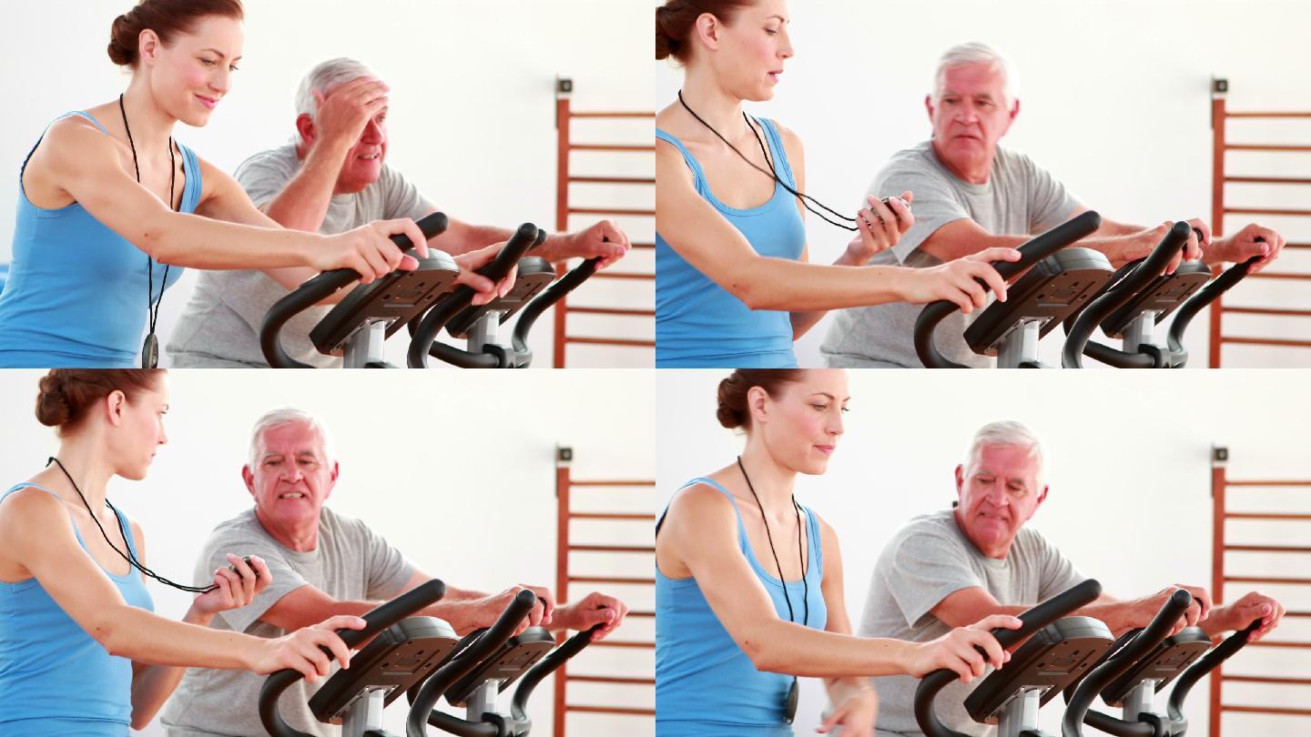 一个老人和他的教练在康复中心使用健身自行车