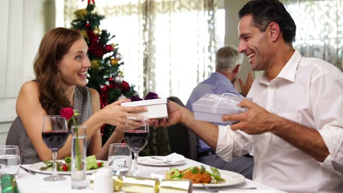 幸福的夫妇一起吃圣诞大餐，并在餐厅交换礼物