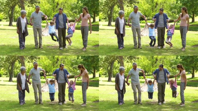 多代同堂的一家人在一个阳光明媚的日子里牵手微笑着在公园里