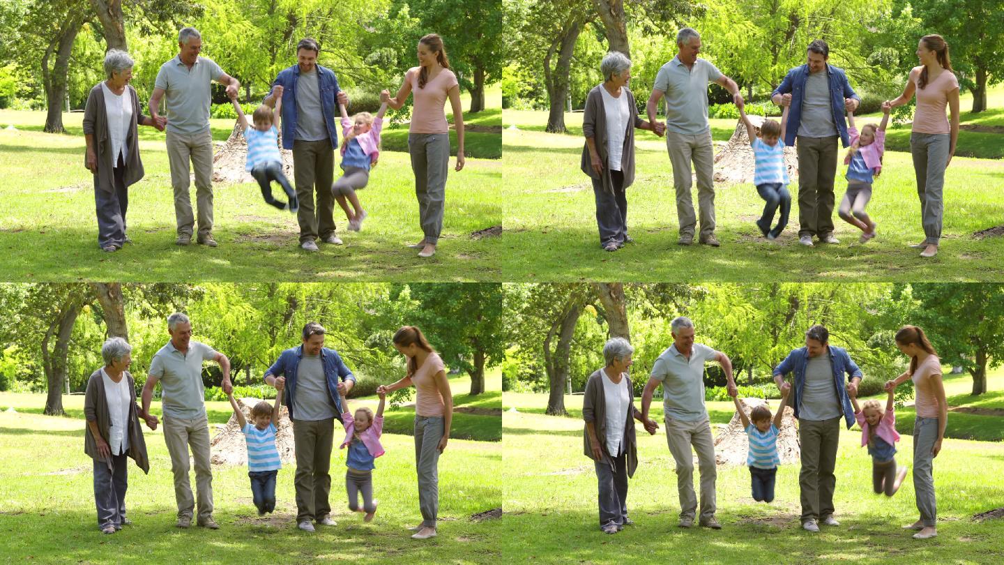 多代同堂的一家人在一个阳光明媚的日子里牵手微笑着在公园里