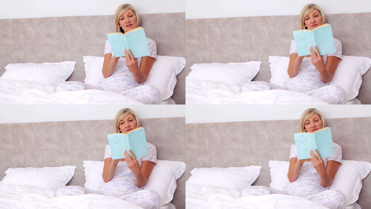 微笑的女人在床上看书在家里的卧室