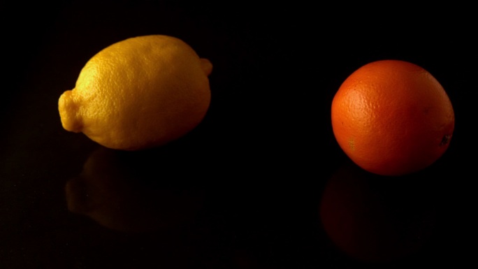柠檬和橙色在黑色表面慢镜头旋转