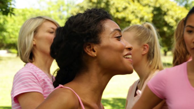 在阳光明媚的日子里，为了提高乳腺癌意识，穿着粉红色衣服的妇女们在公园里聊天