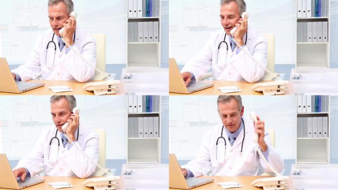 医生在医院办公室的办公桌上打电话和使用笔记本电脑