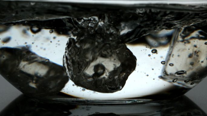 冰块在慢镜头中落入一碗水中