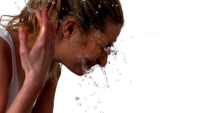 在慢镜头中，一个女人在白色的背景上泼水