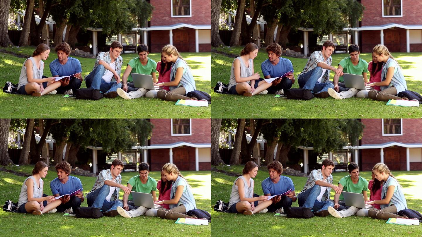 同学们坐在大学里的草地上聊天