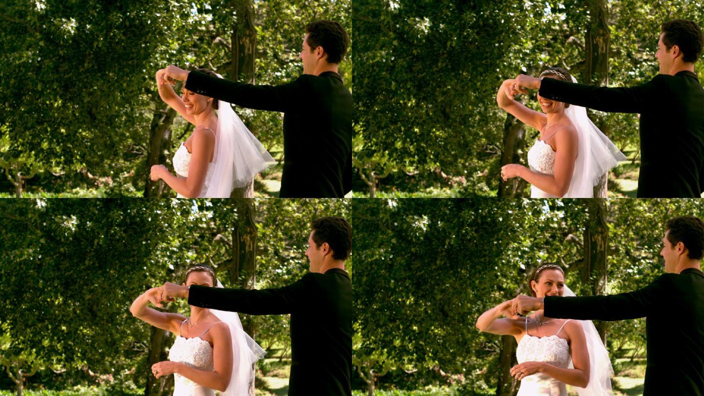 快乐的新婚夫妇在公园里用慢镜头跳舞