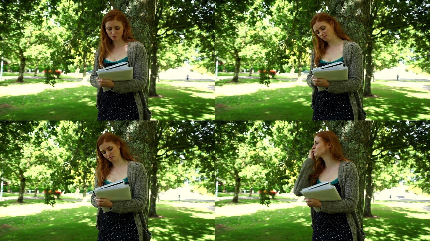 在阳光明媚的日子里，红头发的人站在公园里做作业