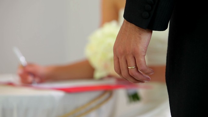 新娘在新郎的注视下签署结婚登记簿