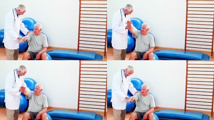 在康复中心，微笑的医生帮助病人移动手臂和肩膀