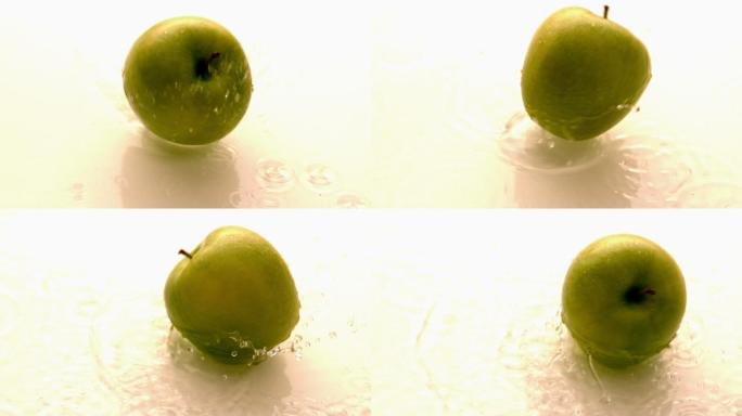 在慢镜头中，苹果在潮湿的白色表面上落下并旋转