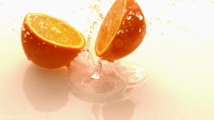 在慢镜头中，橙色的一半在白色潮湿的表面上坠落和弹跳