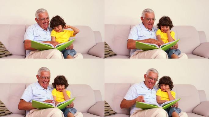 老人坐在沙发上，他的孙子在家里的客厅看相册