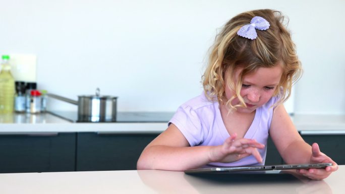 小女孩在厨房里用着平板电脑
