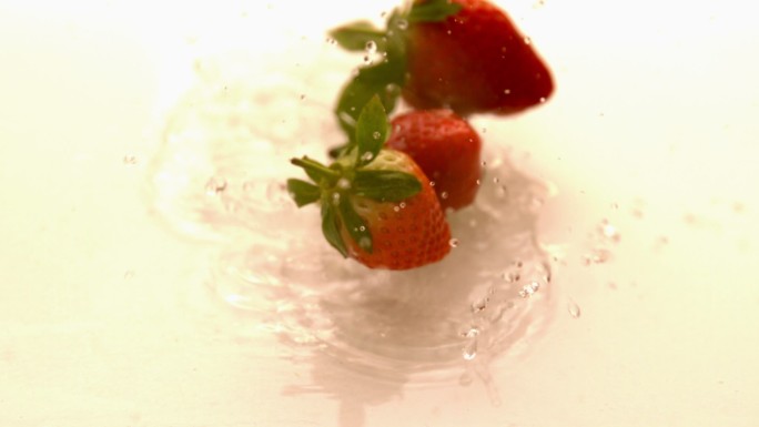 草莓以慢动作落在白色潮湿的表面上