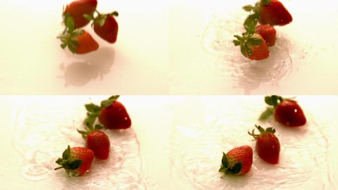 草莓以慢动作落在白色潮湿的表面上