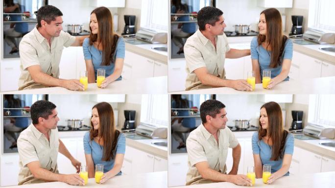 一对夫妇在厨房里喝着橙汁聊天