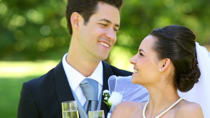 快乐的新婚夫妇在阳光明媚的日子用香槟祝酒