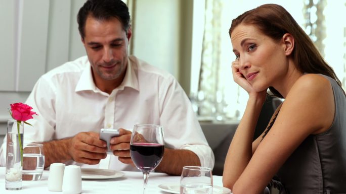 一个无聊的女人在餐馆等她的约会对象停止发短信