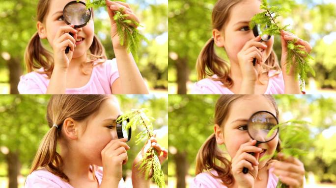 在一个阳光明媚的日子，小女孩透过放大镜看植物