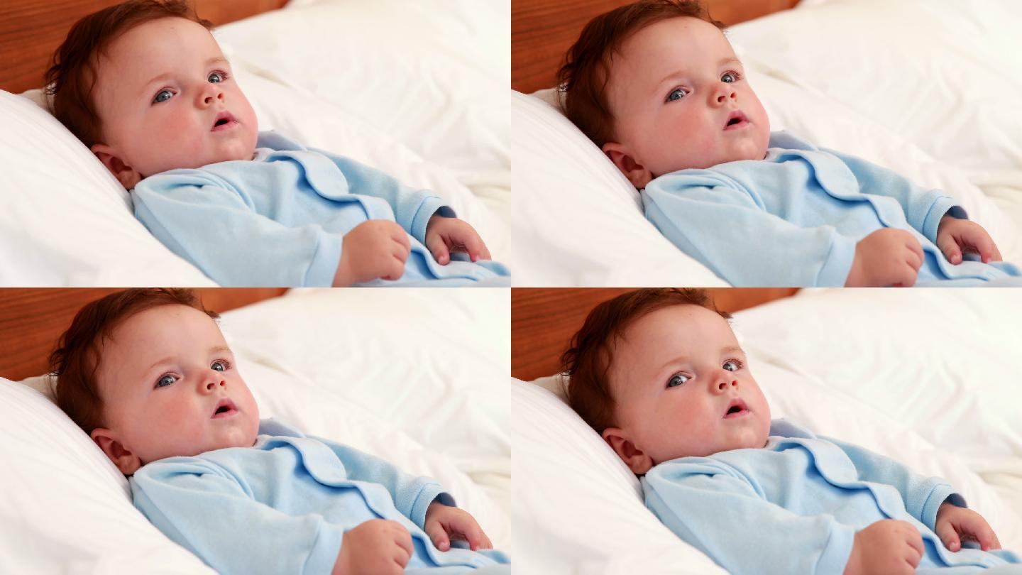 穿蓝色婴儿服的男婴躺在家里卧室的床上