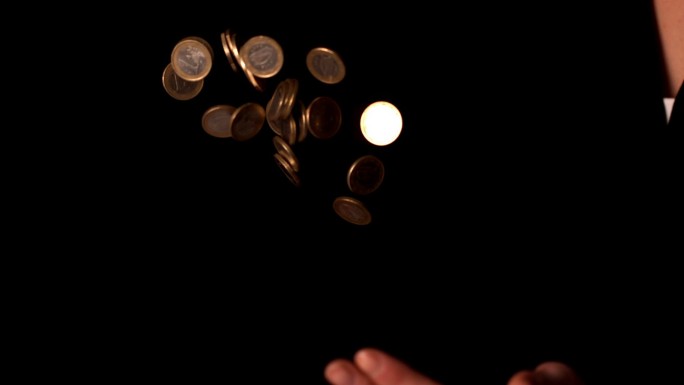 在慢镜头中，一名女子在黑色背景上投掷欧元硬币