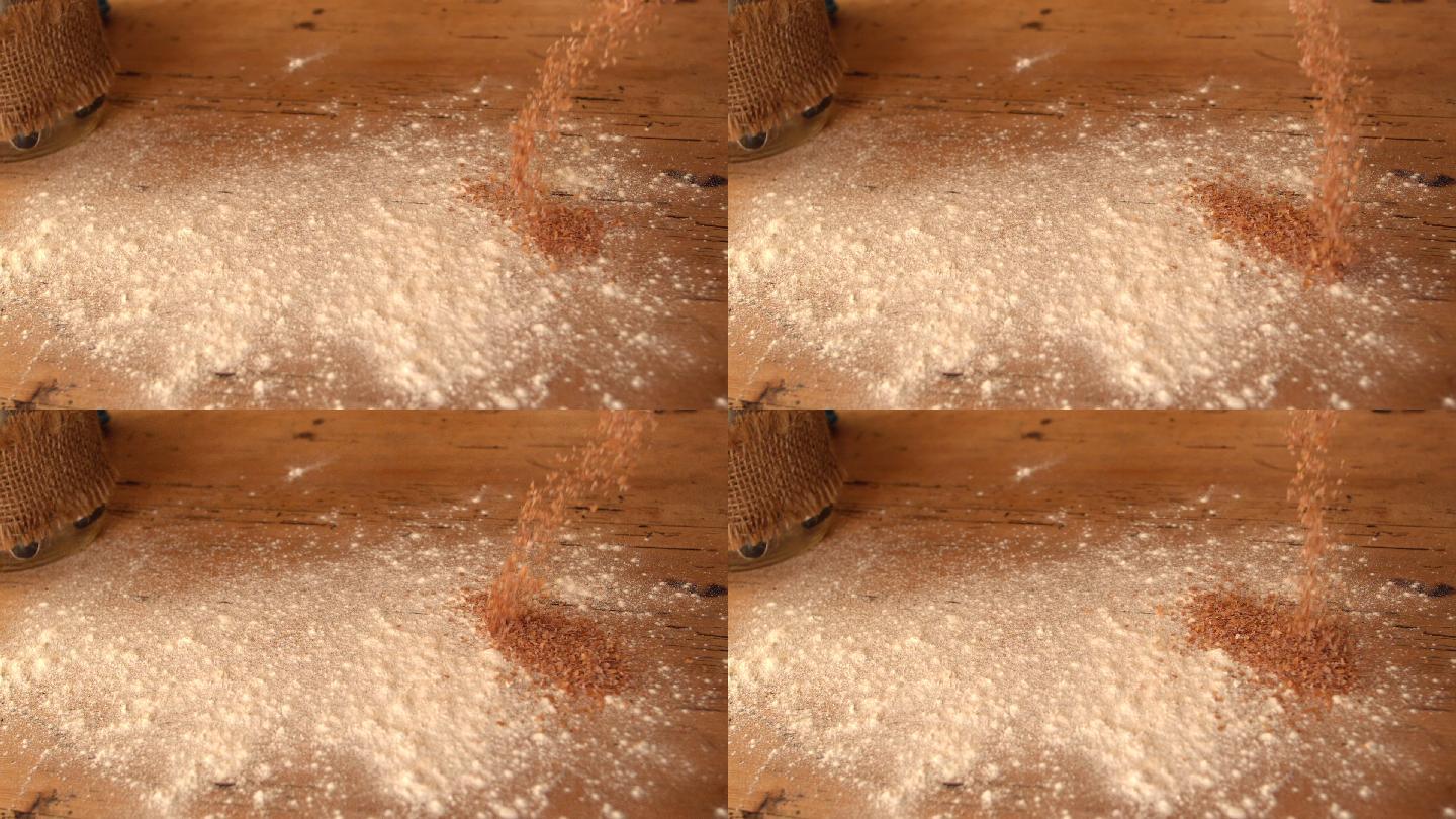 慢动作将面粉和麸皮撒在木制的工作台上