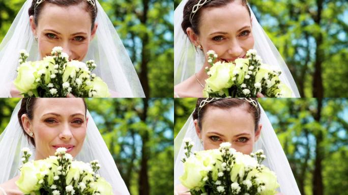 漂亮的新娘在她的婚礼上对着镜头微笑，闻着她的花束