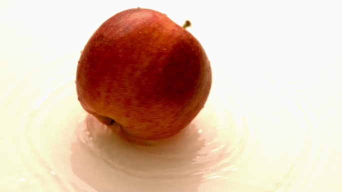 慢镜头中，苹果在潮湿的白色表面上旋转