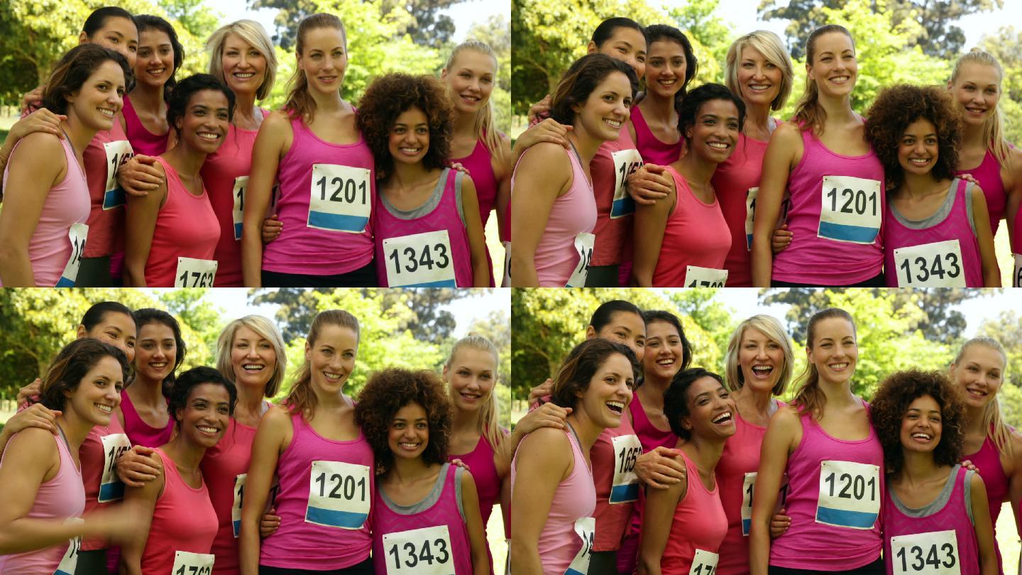在一个阳光明媚的日子里，一名微笑的女子在公园里为乳腺癌意识进行粉色赛跑