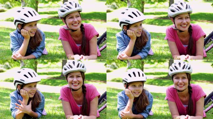 在一个阳光明媚的日子，妈妈和女儿在公园里骑自行车休息