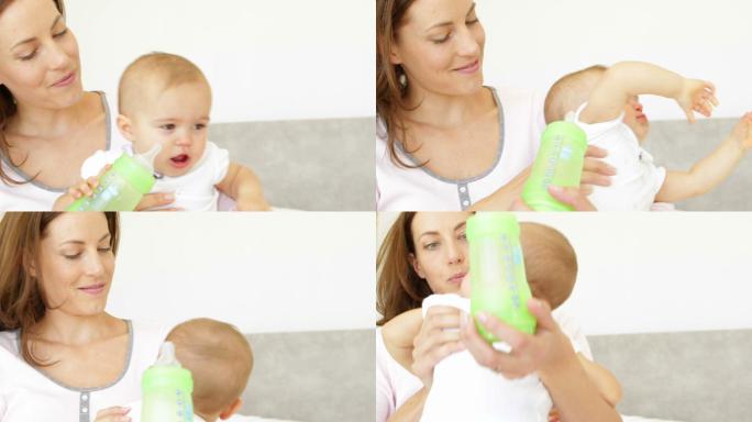 年轻漂亮的妈妈在卧室里给女儿喂奶瓶