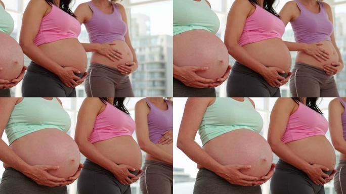 孕妇们站在健身房里拿着她们的肿块
