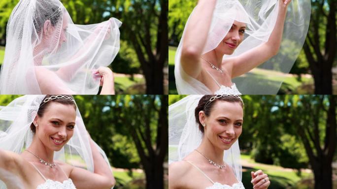 美丽的新娘对着镜头微笑，在她的婚礼上揭开她的面纱
