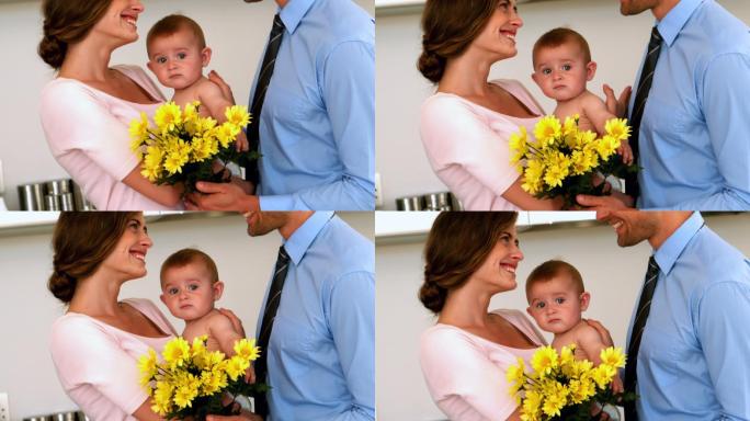 慢镜头中，母亲抱着婴儿，父亲捧着黄花