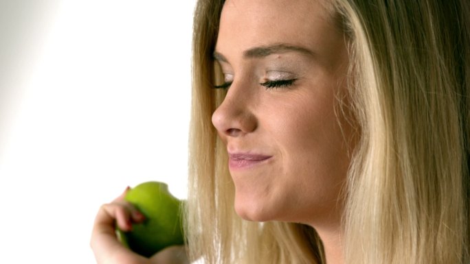 一个金发美女在慢镜头里吃着青苹果