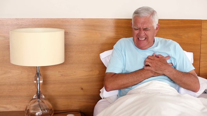 老人坐在床上心脏病发作在家的卧室里