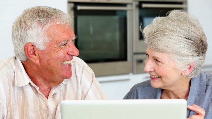 一对老年夫妇在厨房里一起使用笔记本电脑