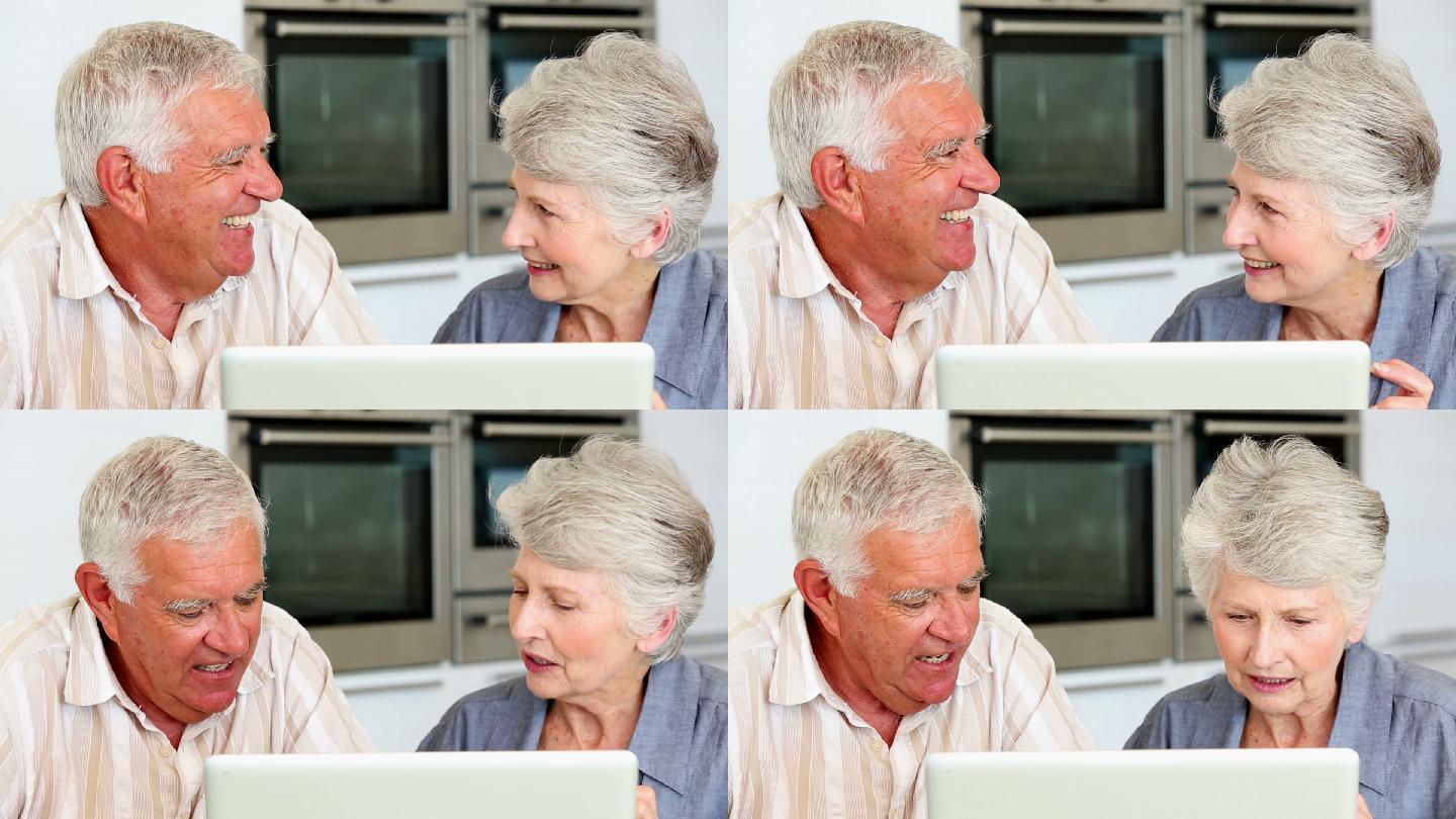 一对老年夫妇在厨房里一起使用笔记本电脑