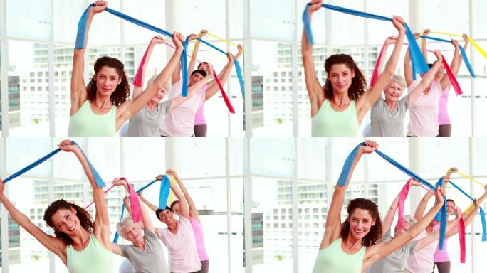 在健身房的健身课上，妇女们在拉伸阻力带