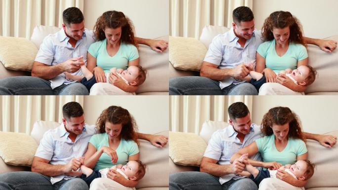 一对幸福的夫妇坐在沙发上，他们的小宝宝在客厅里