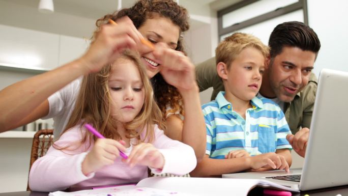 快乐的孩子们在餐桌上和父母一起画画，在厨房里用笔记本电脑
