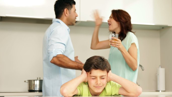 父母在厨房吵架时，心烦意乱的男孩捂着耳朵